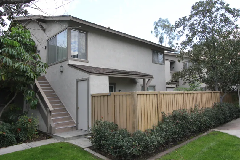Side to the house in Park Vista has trees and plants with flowers and front has meadows