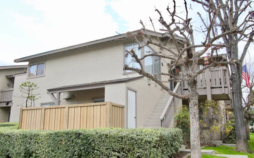 Front of a two story appartment complex. Two baren trees on the right side of the frame.