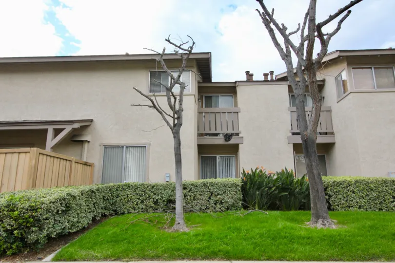 A cloudy day in Park Vista with a house with balconies and trees and hedges in the yard