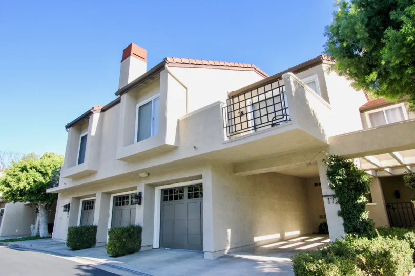 Large three car garage home with lush green landscape and modern exterior. Located in Irvine, CA. Offers a balcony overlooking front side of home.