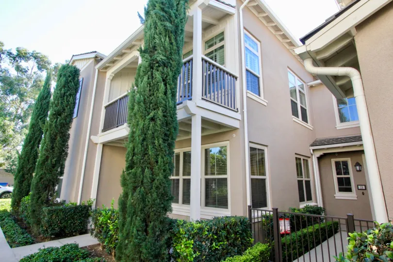A corner view of a three-storey unit in Santa Rosa community with tall shrubs,