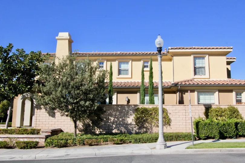 2 story home with many windows, brick fence enclosure, shade trees, in Stonetree Manor.