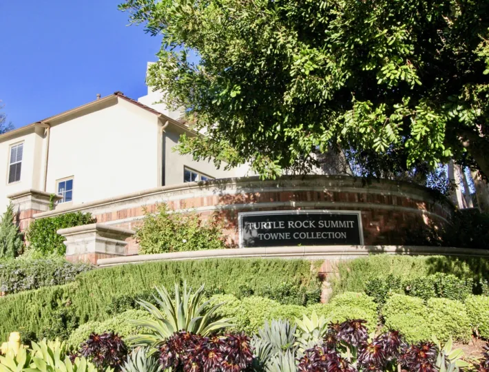 Security wall with community sign on top of a hill outside Summit Towne Collection in Irvine CA
