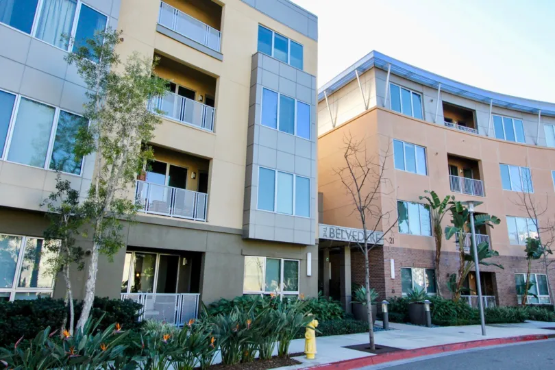 Apartment complex with trees and flowers out front by the road