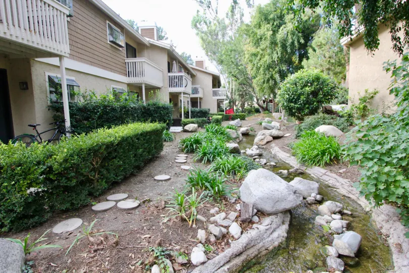 A small stream with rocks running behind apartment buildings
