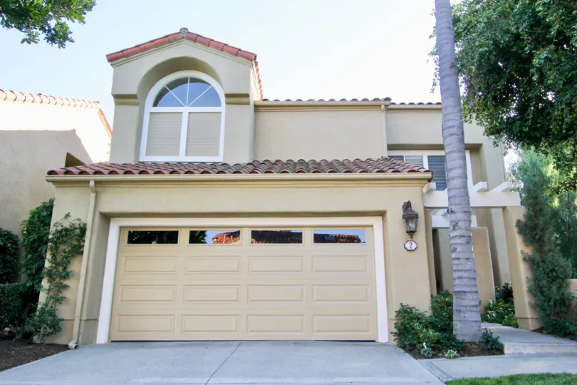 a tan home in Turtle Rock Pointe with a palm tree and a large window