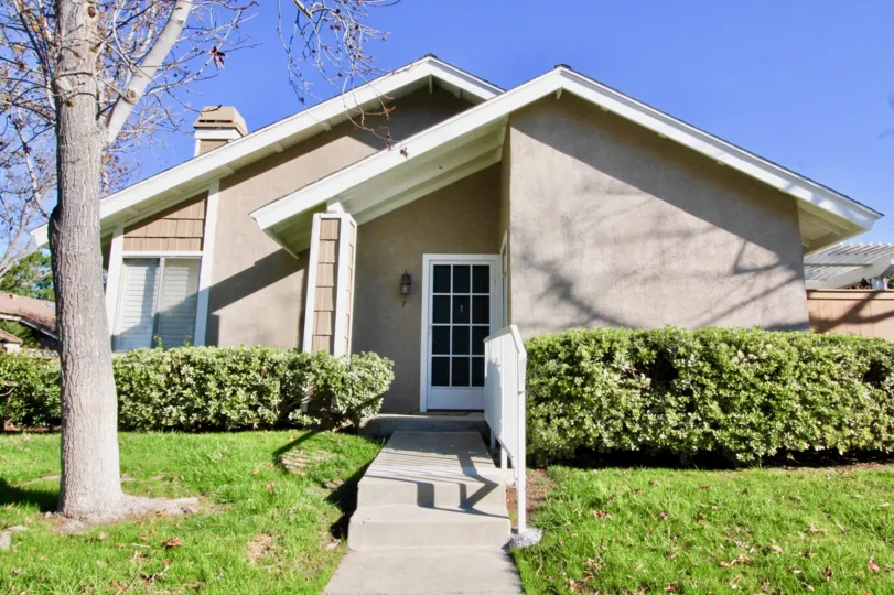 a home in Village Glen with a white framed glass door, white railing, and bare tree