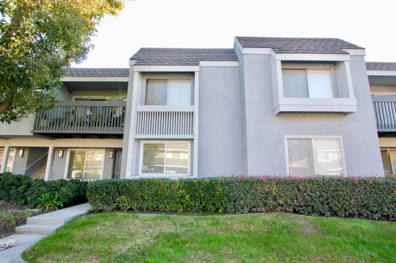 The front of an apartment with trees and shrubs at Village Green in Irvine, California