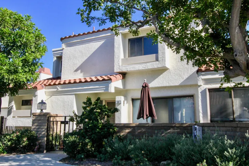 Two story housing with umbrella covered seating area at Villas at RSJ in Irvine CA