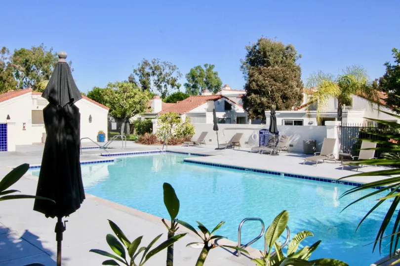 A pool in the Villas at RSJ community surrounded by white houses.