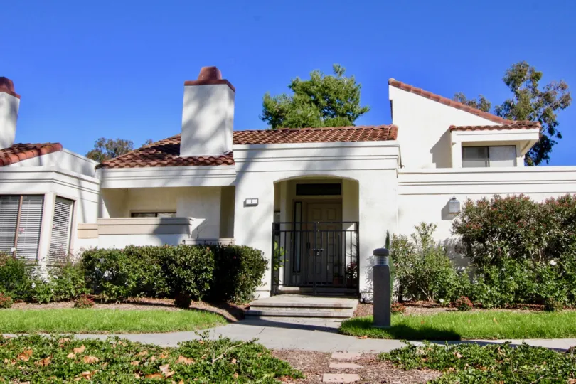 THE FRONT OF THE HOME WITH BEAUTIFUL LAWN, PLANTS, BACKSIDE TREES SHOWN IN IRVINE CITY