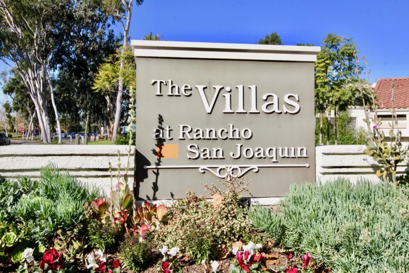 A large gray and white sign behind a garden at Villas at RSL in Irvine CA