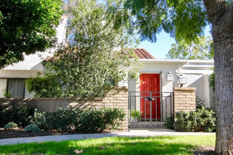 A front view a home with a bright red door in the Villas at RSJ community on a sunny day