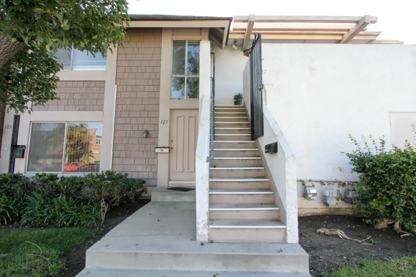a pleasant day in the Walnut Square with a house that has steps in the center garden both side and trees are side