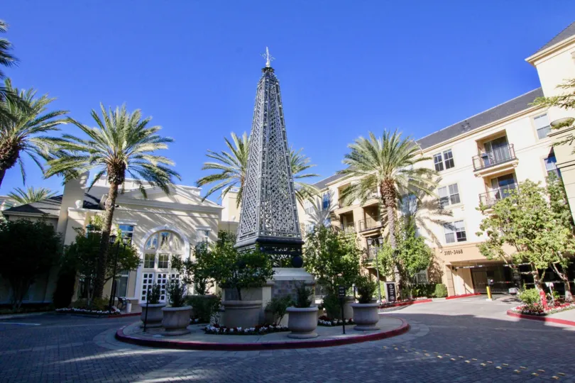 A brick circular drive with a statue of a pyramid shaped tower in the center.