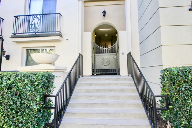 a pleasant day in the watermarke with a building that has steps in the center with a gardens on both side and a balcony on the left side of the steps