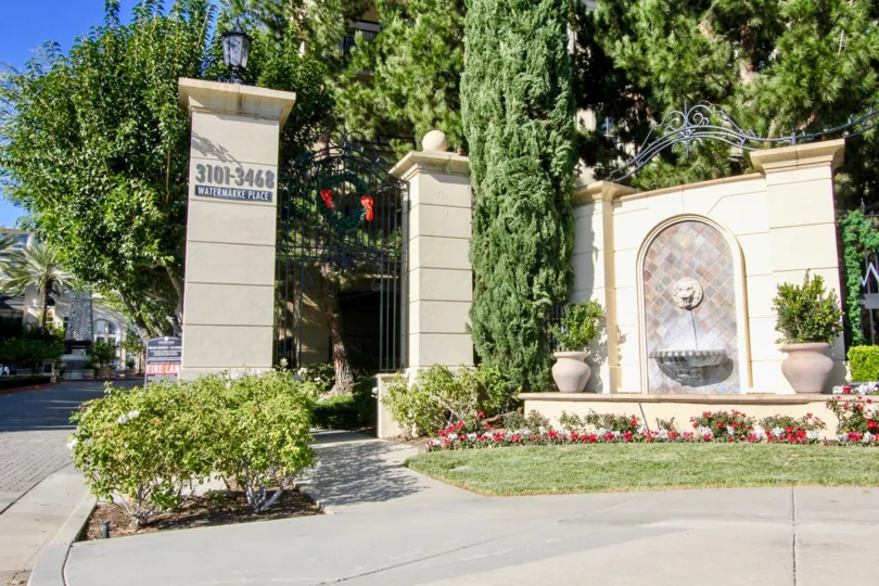 The entrance post to Watermarke with flowers, trees and fountain