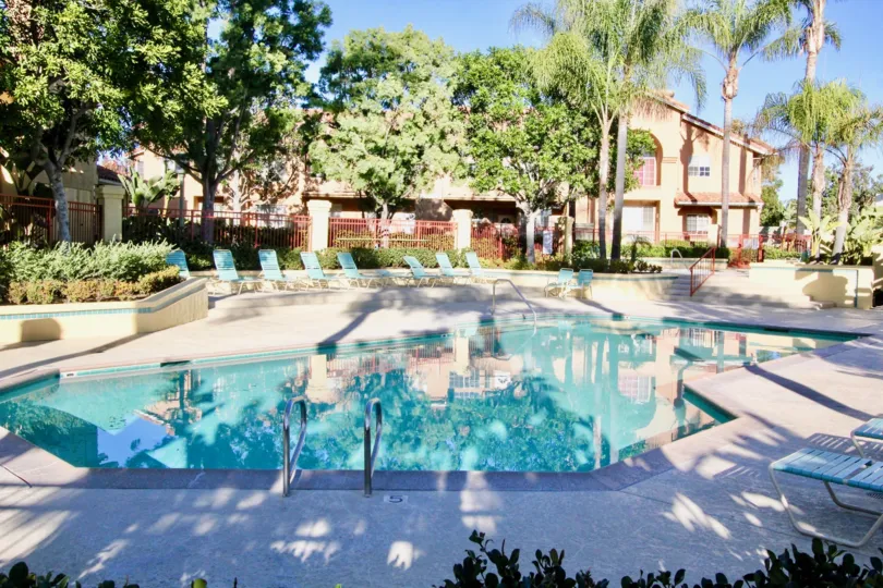 A clear blue swimming pool outside of a large house in Irvine California.