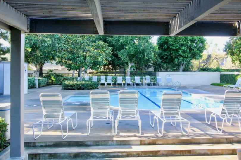 THE BEAUTIFUL SWIMMING POOL WITH LOT OF CHAIRS, BACKSIDE MANY TREES, PLANTS ARE VISIBLE IN IRVINE CITY