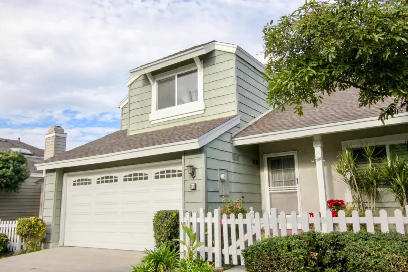 Cloudy day view of gray house with garage at Windwood Garden Homes in Irvine, California