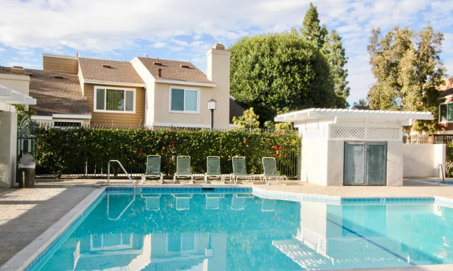 A clean and clear pool decorated with chairs inside the compound near building decorated with trees and plants in Windwood Townhomes