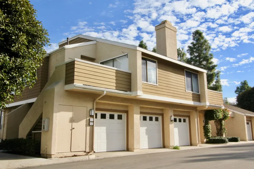 A tan building with three garages in Windwood townhomes community in Irvine, California.