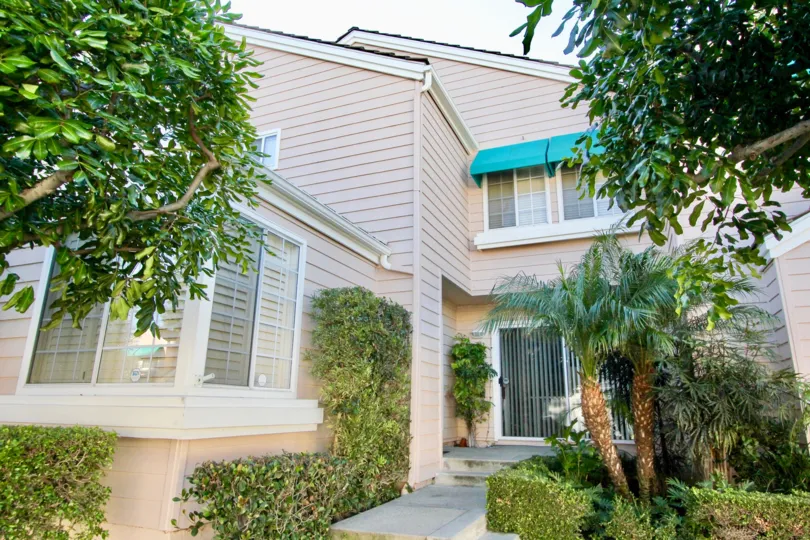 THIS IS THE ENTRANCE TO THE HOUSE WITH LOT OF PLANTS, TREES, MANY GLASS WINDOWS ARE SHOWN IN IRVINE CITY