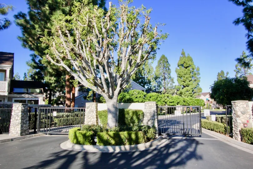 The entrance post to Woodbridge Cove with trees and greenery in Irvine, CA