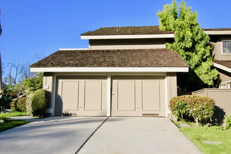 Sunny day looking at two garage doors on a home found in the Woodbridge Crossing community of Irvine, California
