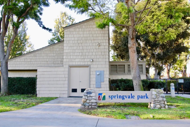 A street view of a sign and common area building and trees at Woodbridge Crossing