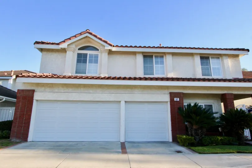 A WARM DAY IN THEWoodbridge Estates WITH A house THAT HAS PARKING DOOR CLOSED AND AROUND THE GARDEN