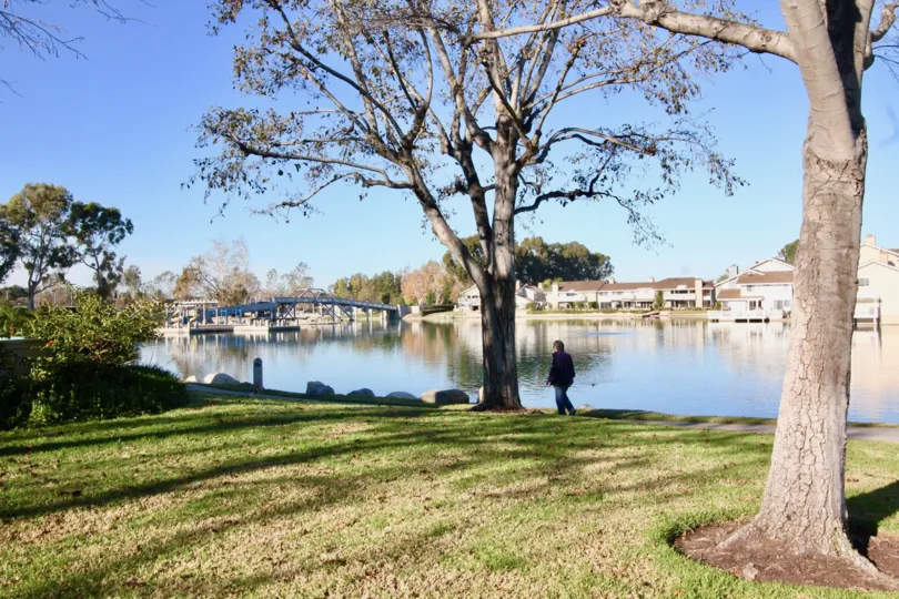A person walking along the water with boats in the Woodbridge Grove community in Irvine, California.