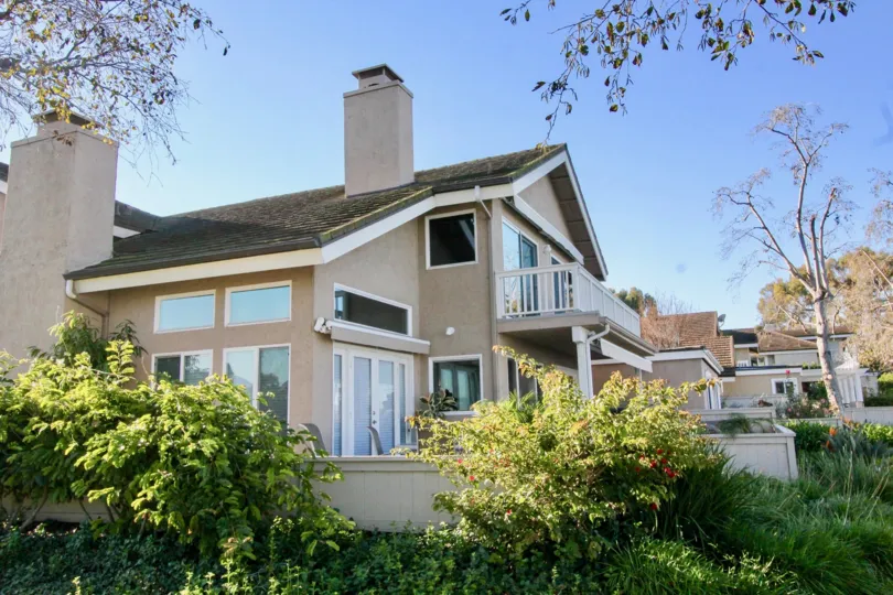 A corner view of a two-storey residence in the Woodbridge Grove community with brown walls and moldy roofs.