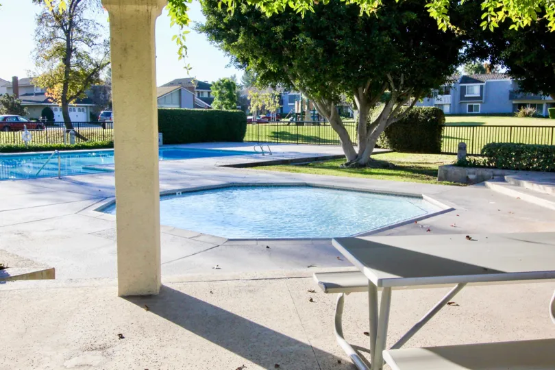 two Swimming pools with trees and open area surrounded by apartments