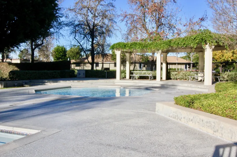 A small polygonal pool in the Woodbridge Grove community with an arbored seating area.