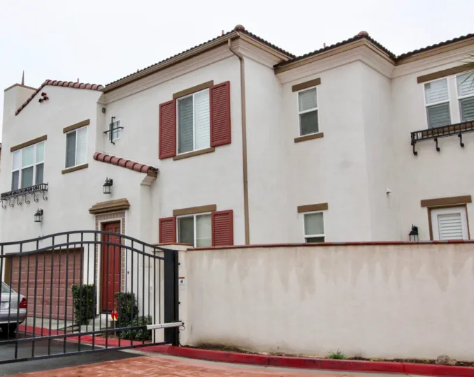 The entrance gate and a white stucco building at the Avo community