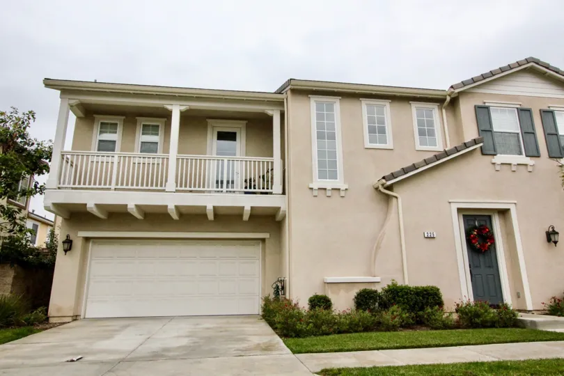 THE FRONT OF THE HOUSE WITH SHED, PALCONY, GLASS WINDOWS, LAWN, PLANTS, BOUQUET ON THE DOOR ARE VISIBLE IN BRIO COMMUNITY