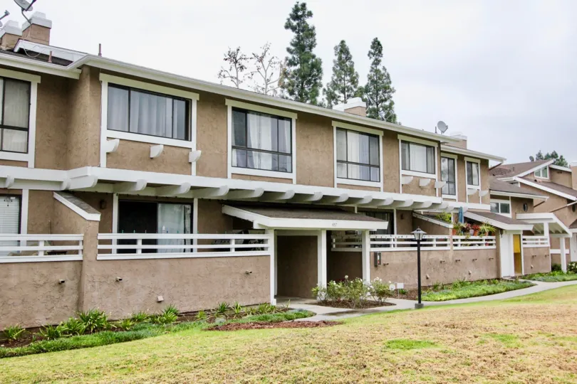 A row of units with their backyard and back walls on a sunny day in the Coyote Creek community