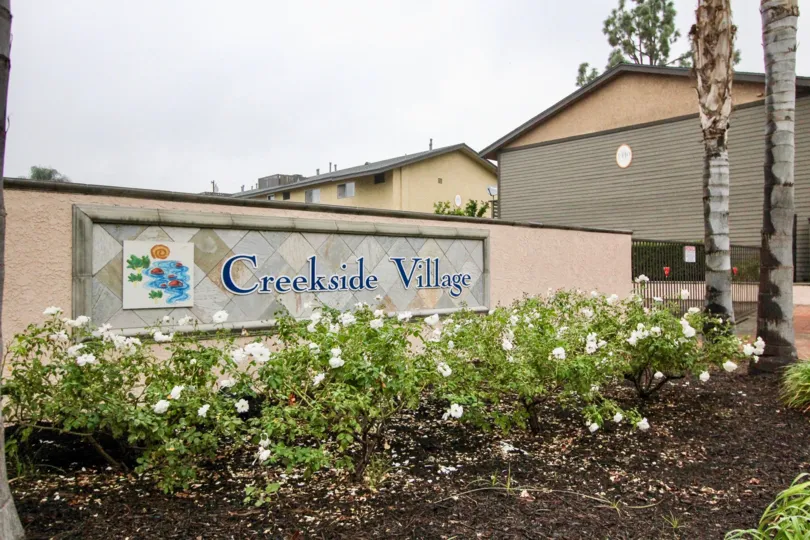 THIS IMAGE SHOWS THE NAME BOARD ON THE WALL NEARBY PLANTS WITH FLOWERS ARE THERE IS IN LA HABRA CITY