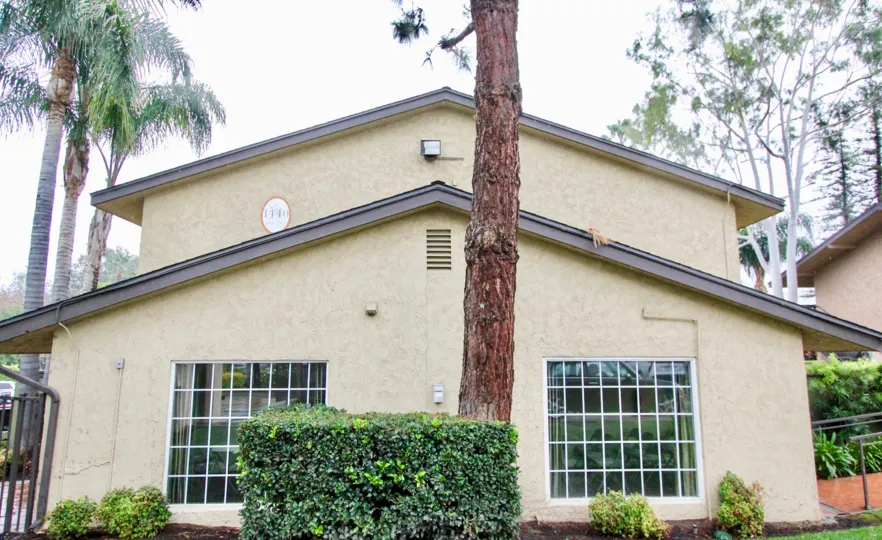 A side view of a home in Creekside Village with large windows and shrubs