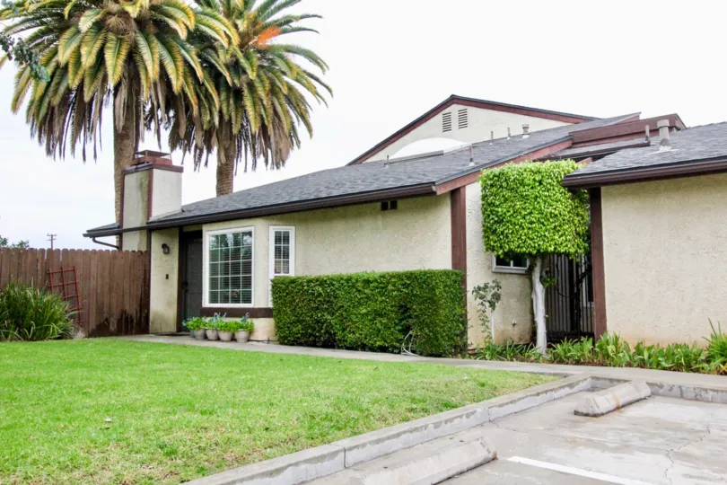 THIS IMAGE SHOWS THE SIDE VIEW OF HOME IN LA HABRA THAT HAVE THE BEAUTIFUL LAWN WITH PLANTS TREES