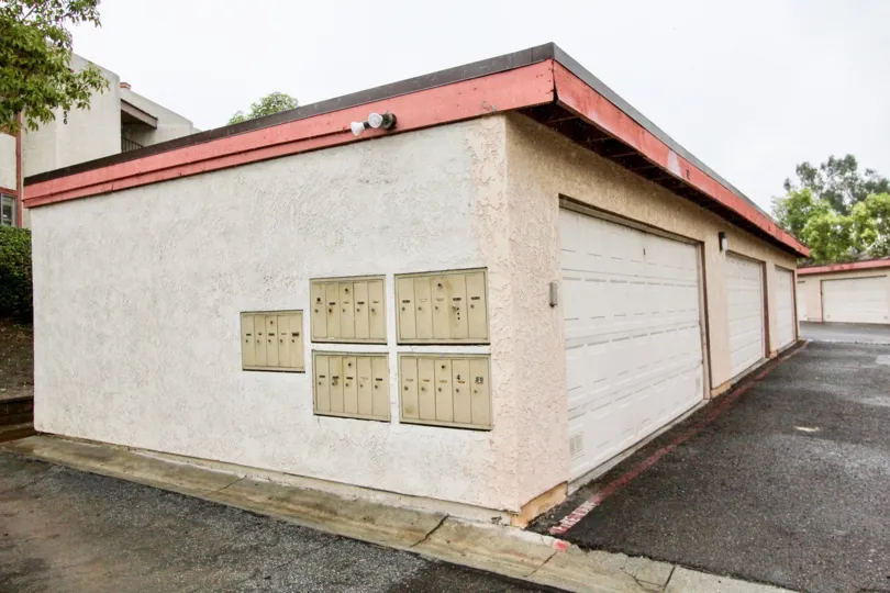 a rainy day in the fashion heights with a building that has 4 parking door closed and trees on the back side