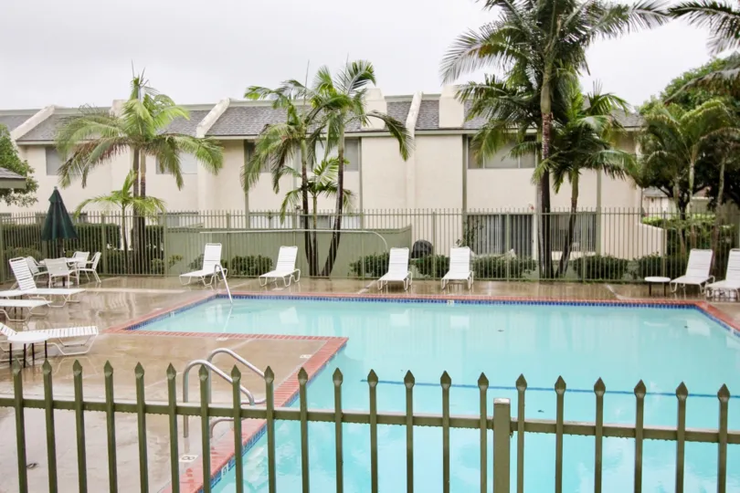 In Heritage village, a Swimming pool with seating chairs and tall trees