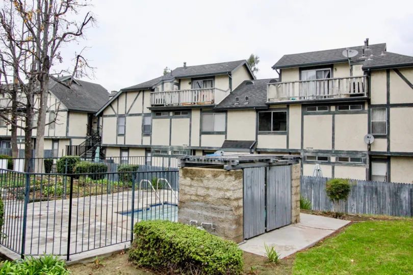 THE BUILDING IN THE HERITAGE WALNUT WITH THE SWIMMING POOL, PLANTS, TREES