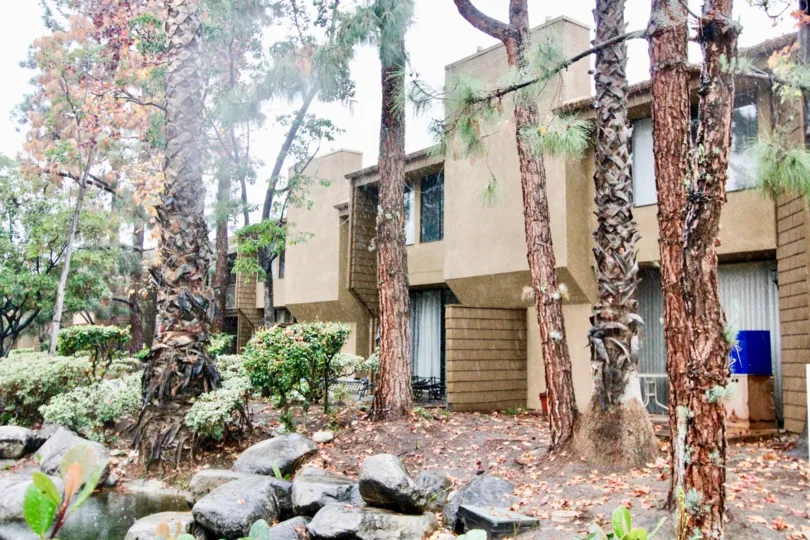 a pleasant day in the hidden lakes with a building that has stones and water on tall trees in front
