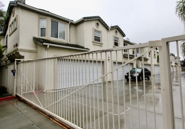 The row home in la habra glen with long gate entrance and cars