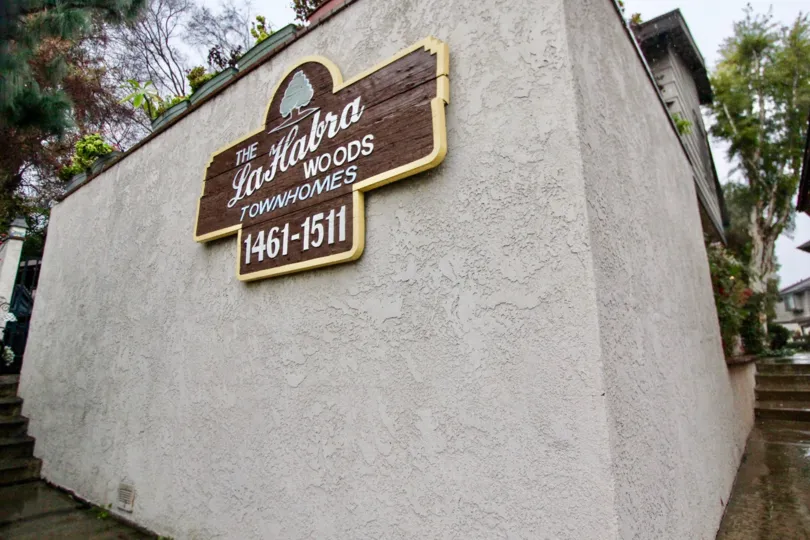 THE ENTRANCE WAY NAME BOARD ON THE WALL BESIDE MANY PLANTS TREES ARE THERE IN LA HABRA CITY