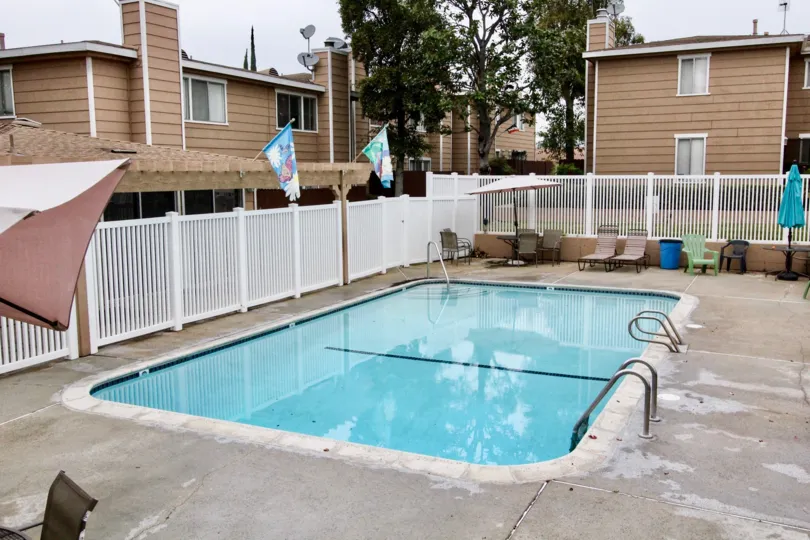 An outdoor pool in the La Plaza Habra area of La Habra, California with umbrellas, lawn chairs, and surrounding townhouse complexes
