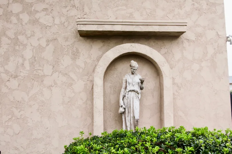 a pleasant day in the la venezia with wall that has statue in it and also plants below the statue
