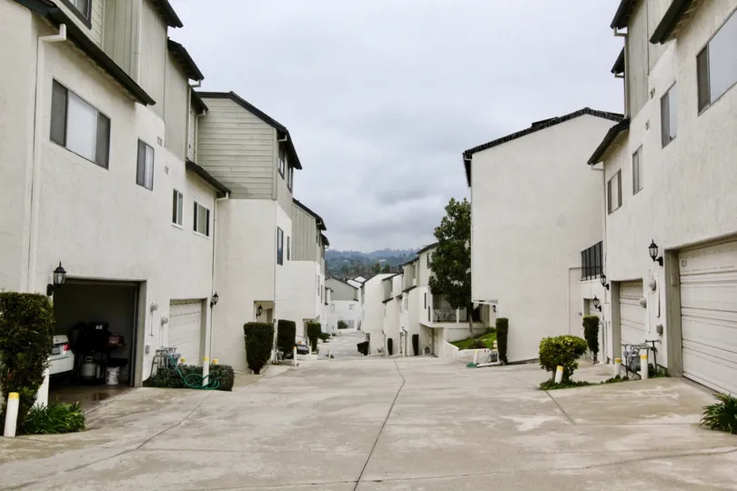 THIS IMAGE VIEWS THE APARTMENTS IN LA HABRA, WHICH HAVE THE SHEDS FOR EACH, PLANTS, AND PATHWAY IS THERE